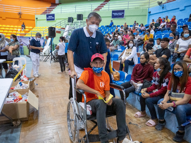 A Tzu Chi volunteer helps Ronald Dela Cruz to get his medicine from the pharmacy. 【Photo by Matt Serrano】