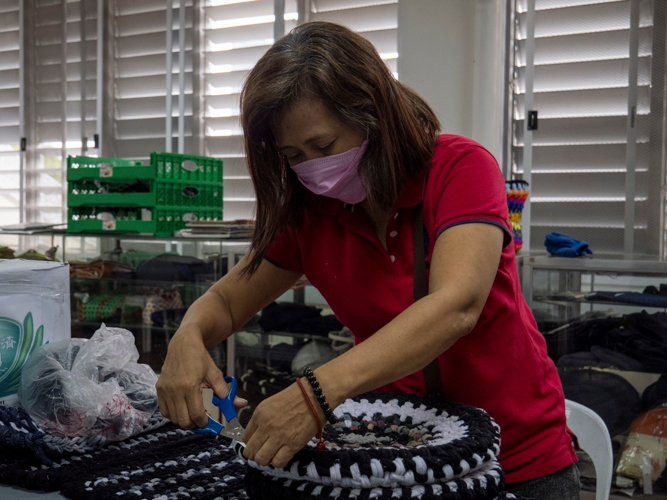 At the Tzu Chi livelihood program room, Esther Co Yu trims a seat cover woven with the excess elastic band of sports socks. 【Photo by Matt Serrano】
