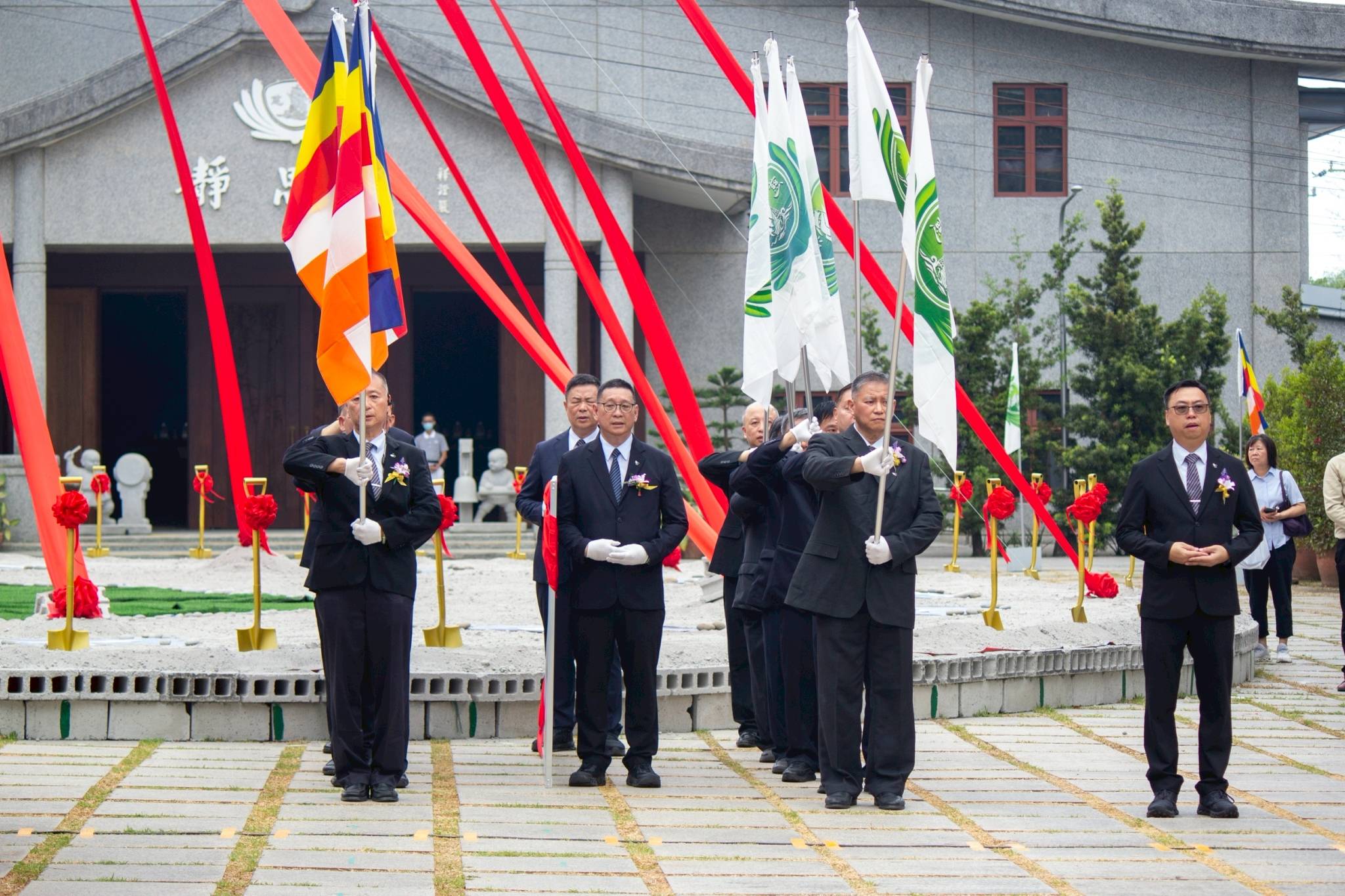 Tzu Chi volunteers prepare to present the Tzu Chi and Buddhist flags and a perspective of the Tzu Chi Medical Center. 