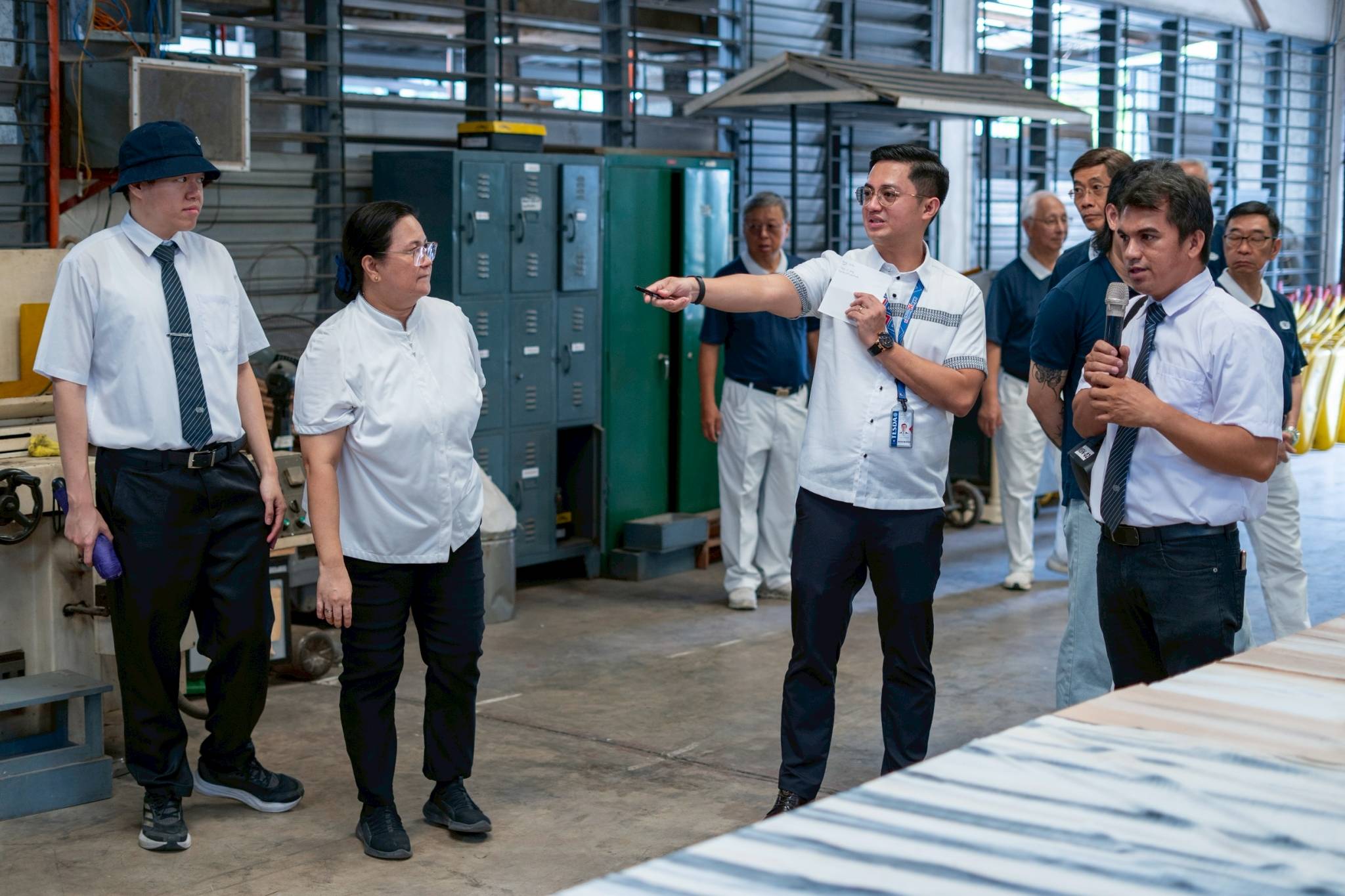 Tzu Chi Tech-Voc scholar-turned-trainer Elpidio Valdez Jr. (first from right) leads TESDA Manila District Director Paul John Ramos on a tour inside the teaching facility for welding. 
