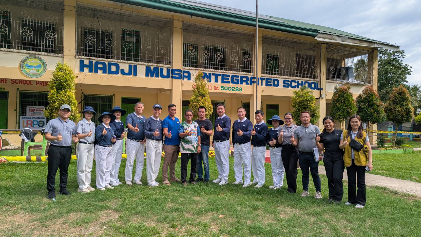 Volunteers pose with locals outside Hadji Musa Integrated School in Glan. 
