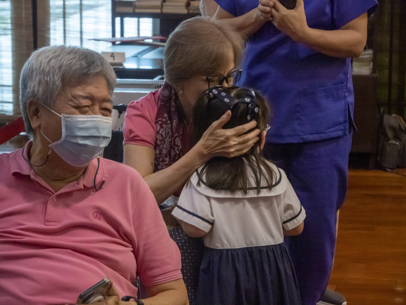 A preschooler gets a sweet kiss from her grandparent. 