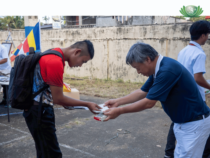 Volunteer Johnny Kwok gives a Puregold gift check to a student. 
