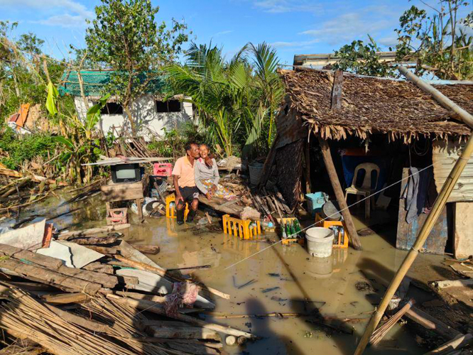 In Bisagu, an elderly couple sit outside their completely damaged house after the typhoon. Despite their loss, they remain hopeful, optimistic, and grateful for their safety.