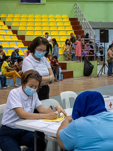 Dr. Rose Go (seated, in white) assesses patients during the medical mission. 【Photo by Dorothy Castro】