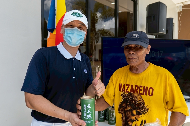 After a successful removal of a benign cyst at the back of his head, Teodoro Mendoza Mercado (right) gives back by placing a donation in Tzu Chi’s coin bank. 