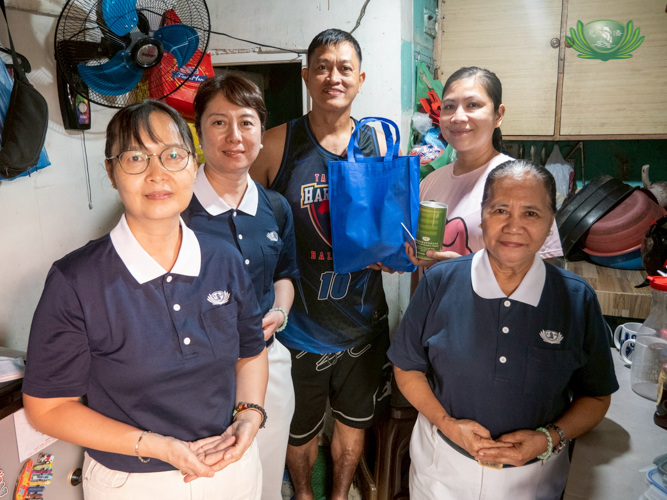 In a recent home visit, Tzu Chi volunteers present a coin can and other tokens to Dennis Cariaga and his wife Lonelyn. 