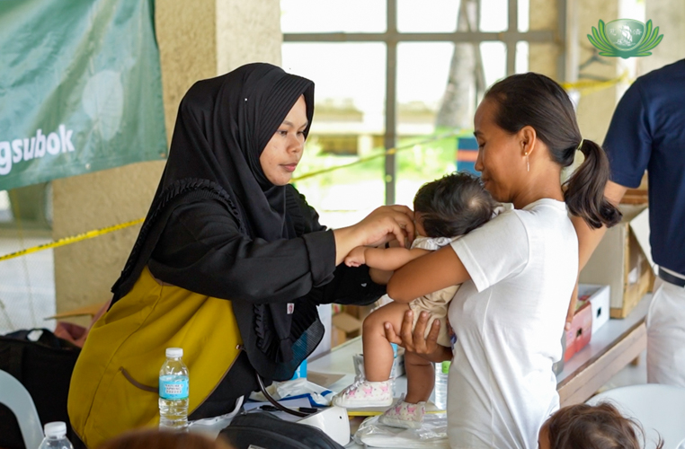 Dr. Rizma Uckung-Luy checks an infant during the relief distribution.