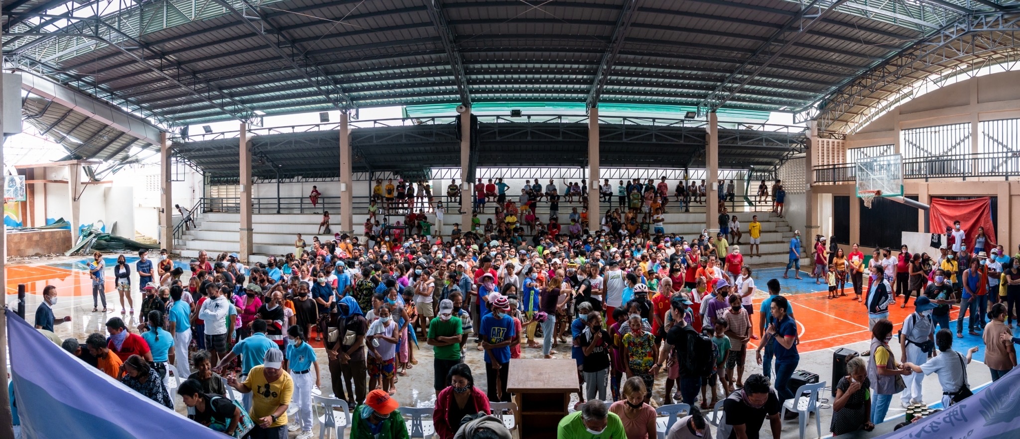 CPG beneficiaries converge in a covered court whose roof was partly destroyed by Odette. 【Photo by Daniel Lazar】