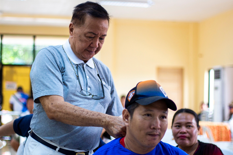 A Tzu Chi volunteer helps the beneficiaries wear their patient gowns in preparation for the prosthesis fitting.