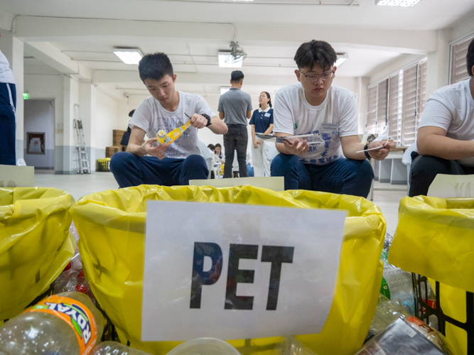 Youth camp participants sort through used bottles and other discarded plastics in the recycling area. 