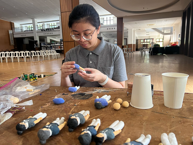 Nathania Brigette So Tan helps sculpt and paint miniature Tzu Chi commissioners and Tzu Chi Youth made of air-dried clay. 