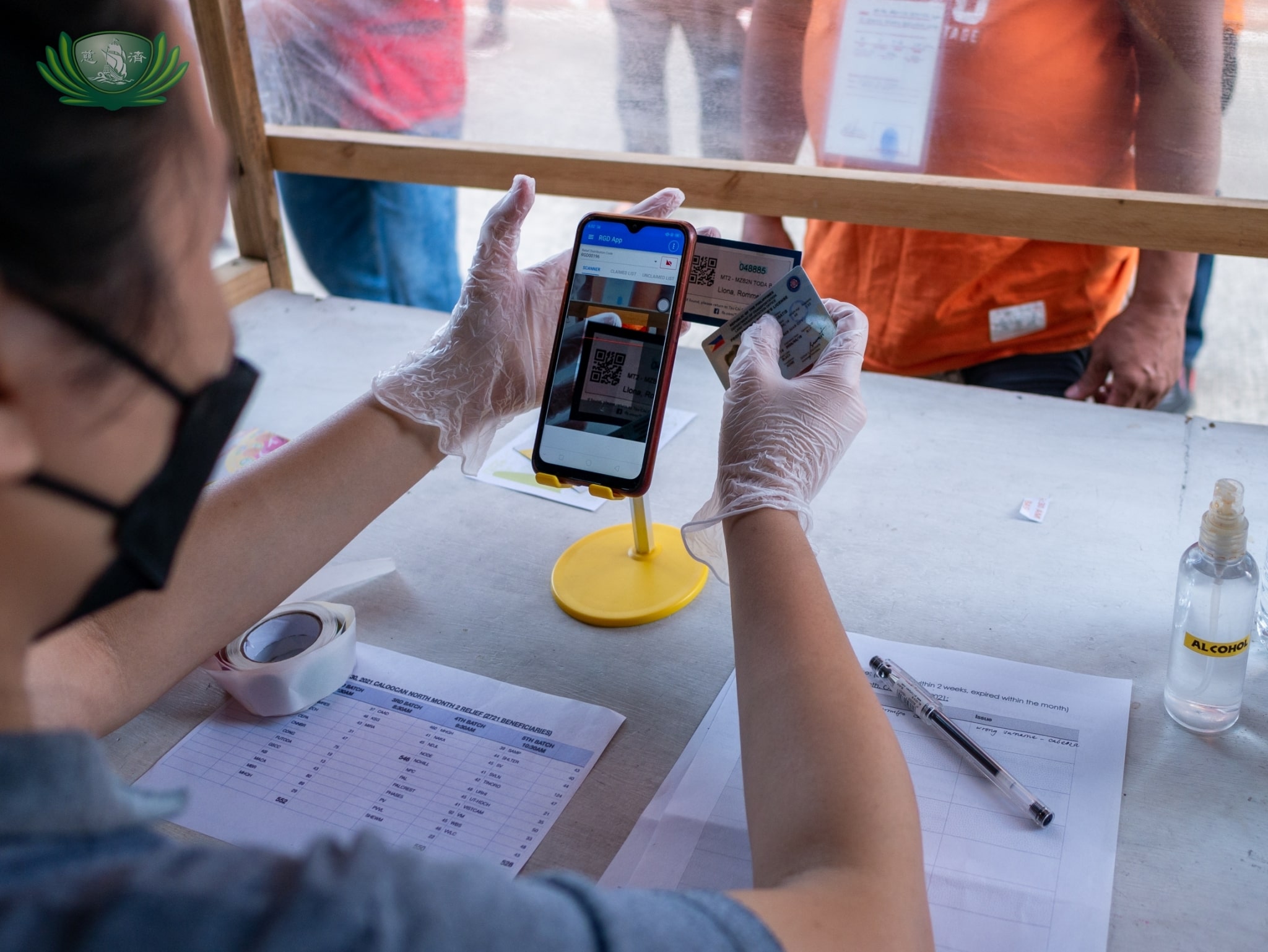 A volunteer uses an app on her cellphone to confirm a driver’s identification. This has made the process of claiming relief goods faster and more efficient. 【Photo by Daniel Lazar】