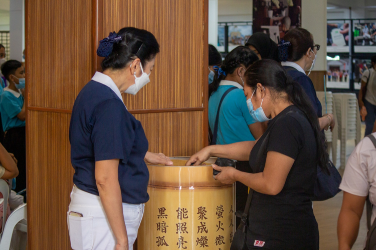Guests drop donated coins in Tzu Chi’s large coin bank. 【Photo by Marella Saldonido】