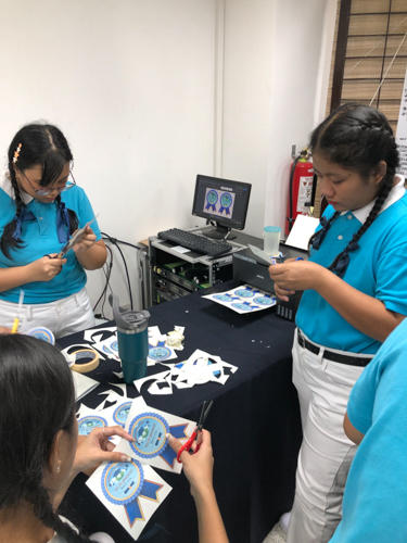 At the Harmony Hall, the camp’s working team print and cut medals for the graduating scholars. 