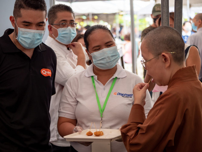 A Buddhist monk samples a serving of Quorn, a brand of plant-based meat made of Mycoprotein. 【Photo by Daniel Lazar】