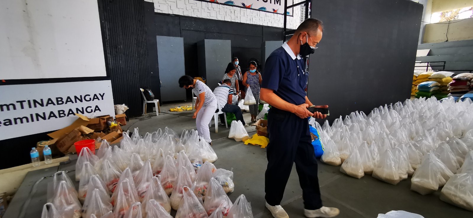 A Tzu Chi volunteer walks past bags of relief aid provided by the local government unit.【Photo by Johnny Kwok】