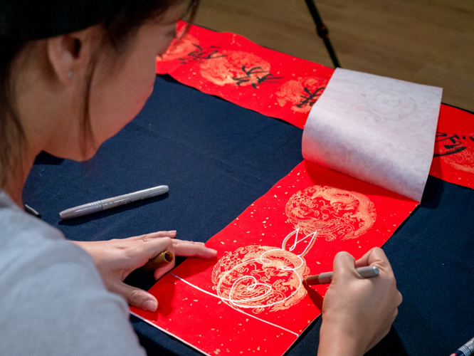 Artist Cindy Siy draws rabbits on a red scroll before it is given to a calligrapher. 【Photo by Daniel Lazar】