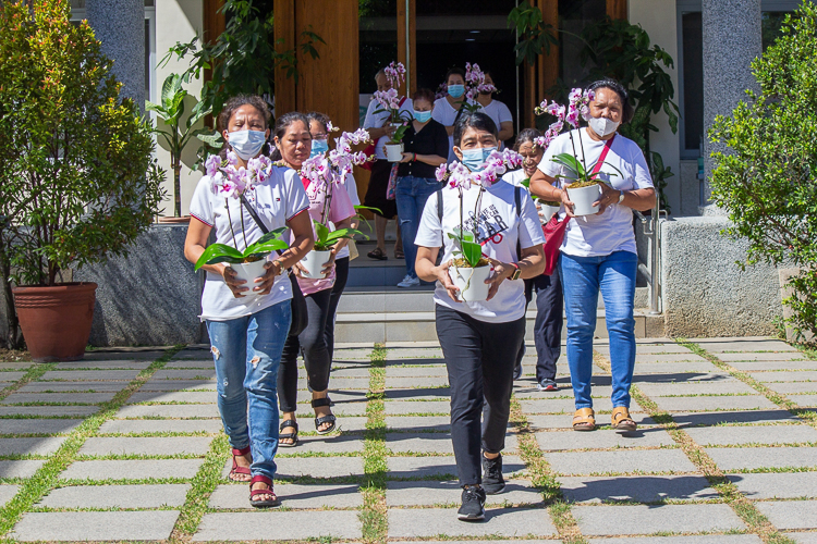 Tzu Chi scholars' mothers help out in the preparations by bringing potted orchids to the Buddha Bathing Ceremony tables.