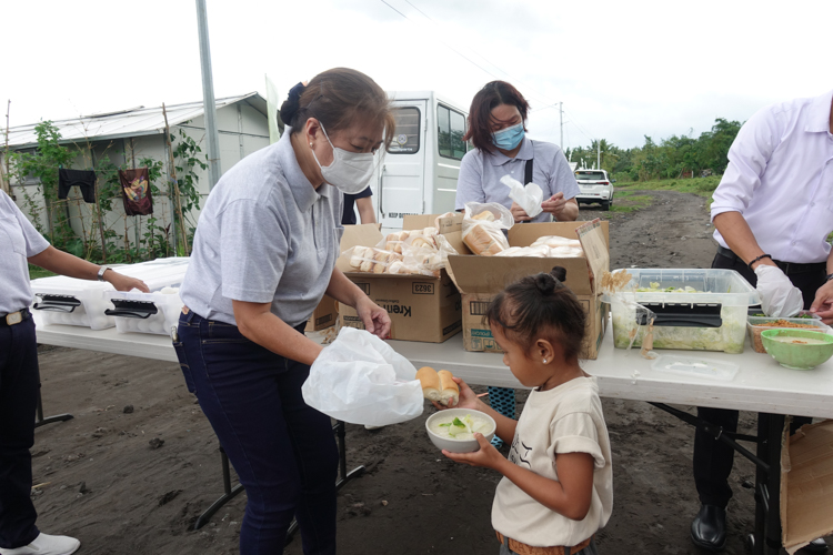 A Tzu Chi volunteer in Bicol offers bread and hot porridge to a little girl. 