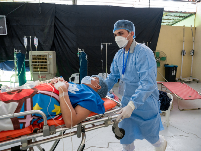 Tzu Chi Zamboanga volunteer Brian Pioquinto carries a patient to the Post-Anesthesia Care Unit. 【Photo by Daniel Lazar】