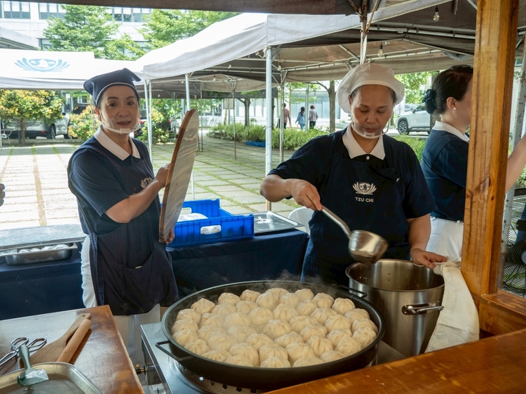 A volunteer lifts the lid off a pan of fried vegetarian bun.