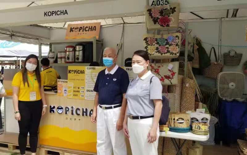 Tzu Chi CEO Henry Yuñez is flanked by Sharmaine Tan (left) and Therese Tan (right) at the Kopicha booth. 