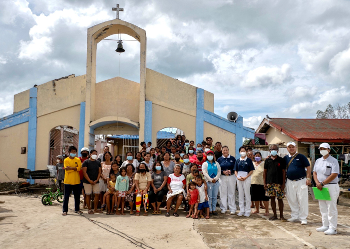 With the local church as their backdrop, volunteers pose with the residents of Barangay Lawis. 【Photo by Marella Saldonido】