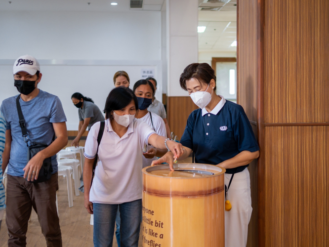 A mother places her pledge in a large collection container. 【Photo by Matt Serrano】