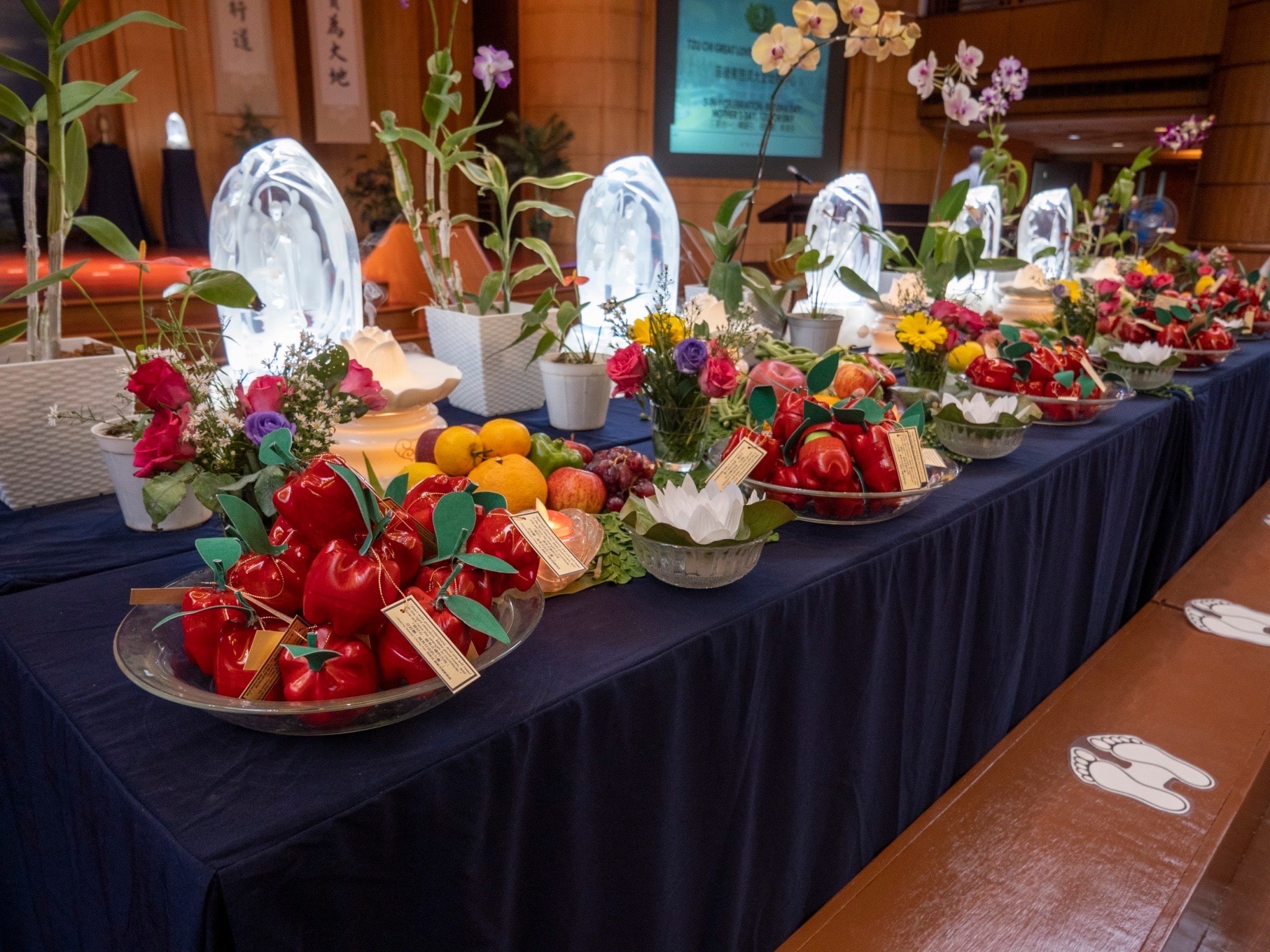 Crystal Buddhas on the table are adorned with fruits, vegetables, and fresh flowers, while recycled plastic fruits designed and painted by the students serve as souvenir for participants. 【Photo by Matt Serrano】