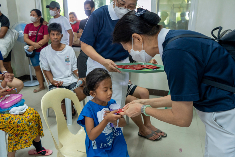 Volunteers distribute tokens from Tzu Chi Founder Dharma Master Cheng Yen—an ampao (red envelope) and an aphorism with a charm.