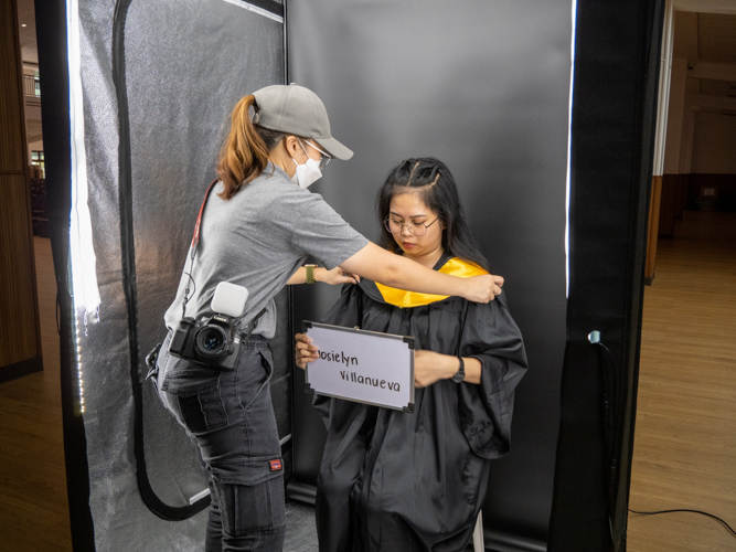 A college senior is being prepped for a formal graduation photo.【Photo by Matt Serrano】
