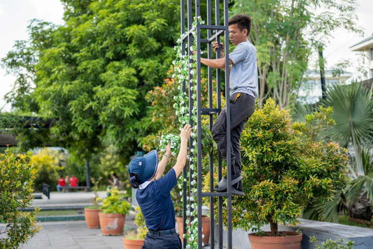 A Tzu Chi maintenance man climbs the frame of the Fiesta Verde arch to decorate it with a garland of flowers. 