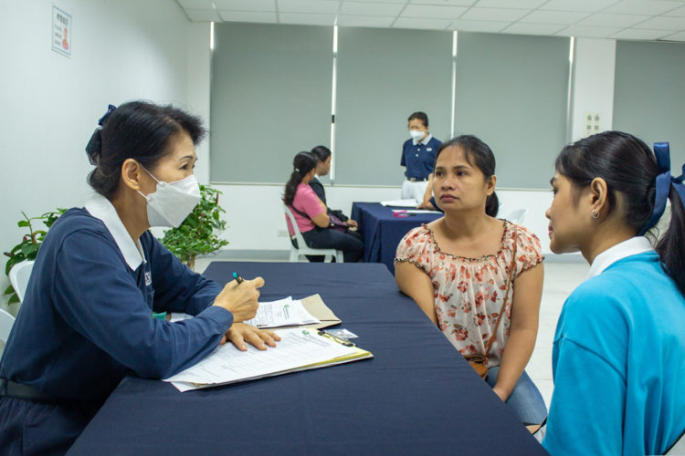 Tzu Chi Philippines Deputy CEO Woon Ng (left) interviews a scholar (right) and her mother. 【Photo by Marella Saldonido】