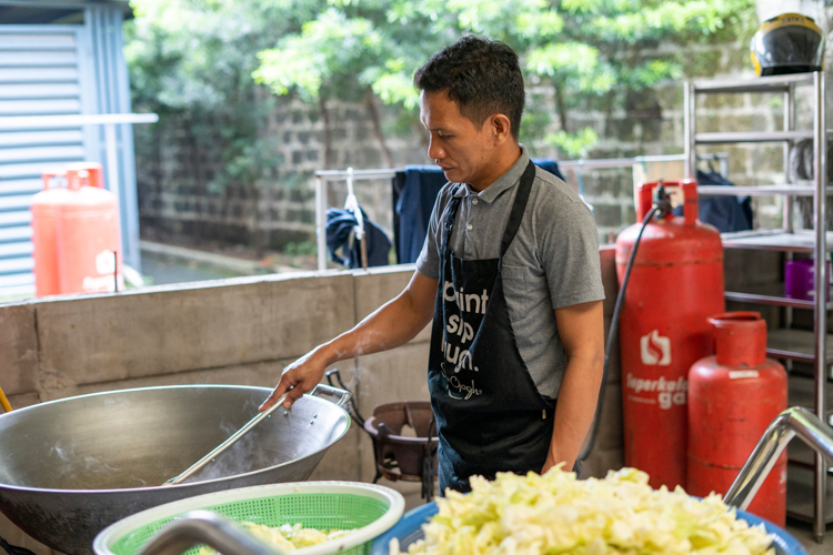 With his ingredients in place, kitchen staffer Jhay-ar Ilo heats up a huge wok to begin cooking.