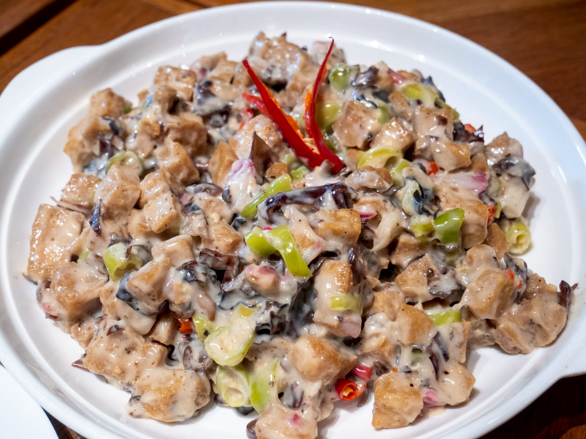 Sisig features stir-fried tofu and mushrooms in a spiced soy-vinegar glaze with a zesty finish.