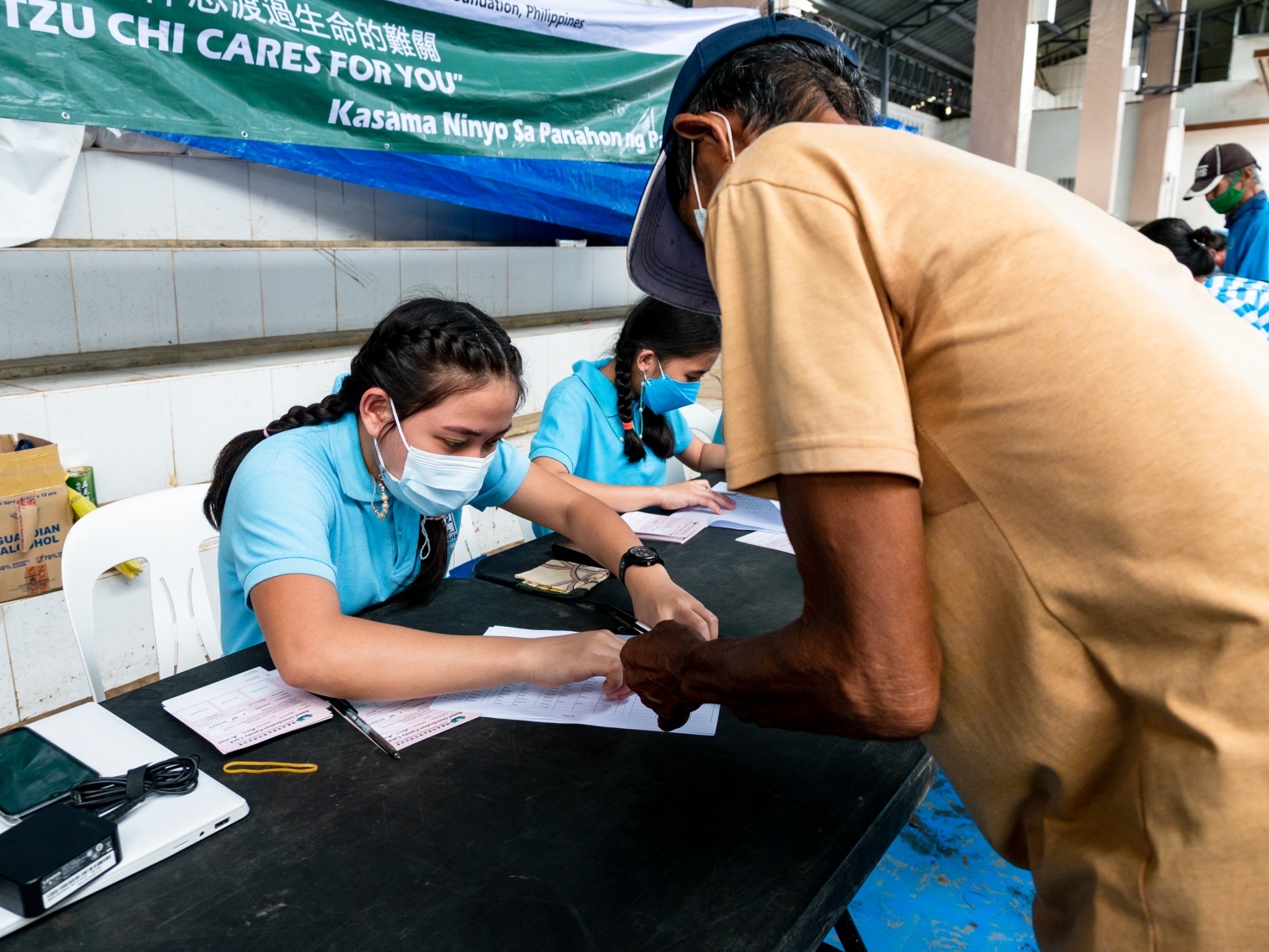 A volunteer scholar assists a beneficiary in claiming his rice relief. 【Photo by Michael Sanchez】