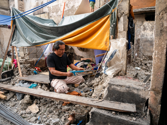 A man salvages what he can of a metal bar to rebuild a new home. 【Photo by Daniel Lazar】