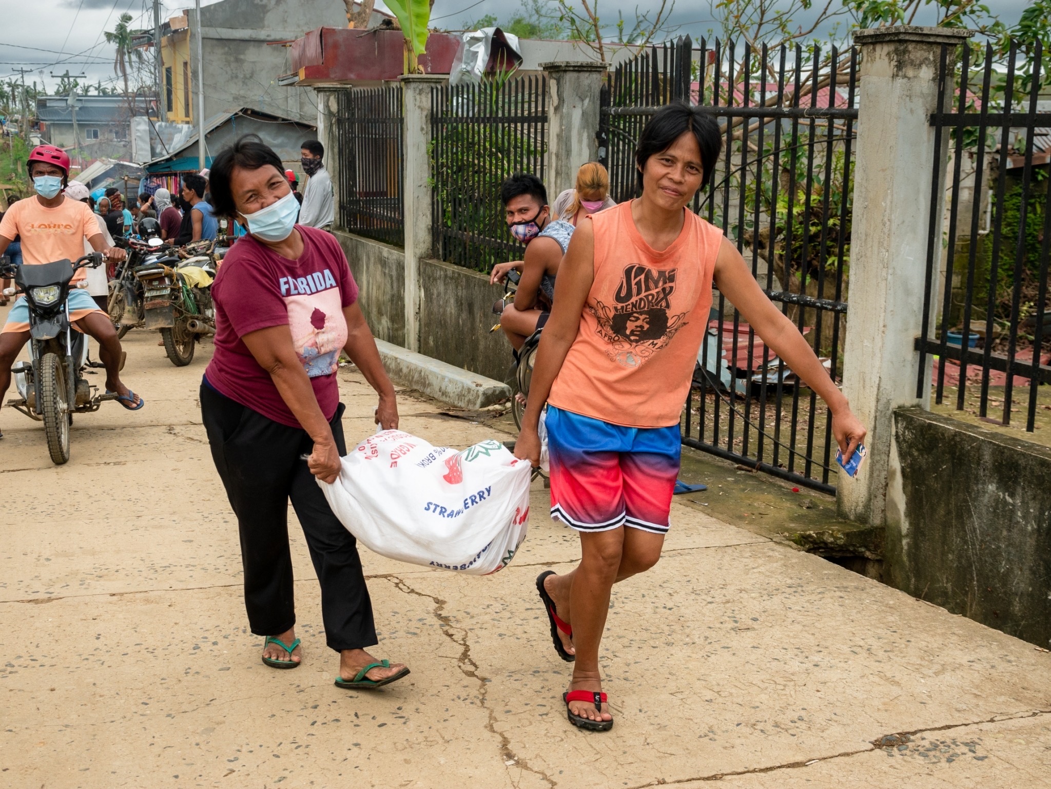 Women help each other lug their rice relief home. 【Photo by Michael Sanchez】