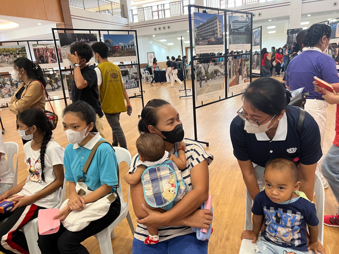 A Tzu Chi commissioner checks on a mother and her children in the pediatric medicine consultation area. 