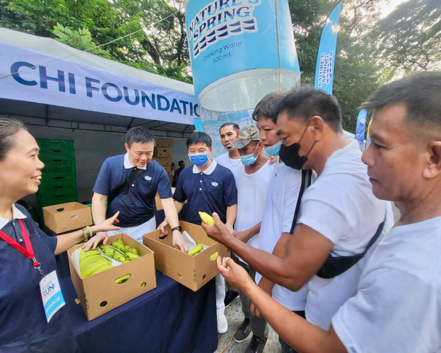 Tzu Chi Davao volunteer Nelson Chua (second from left) helps distribute bananas at the Tzu Chi booth.