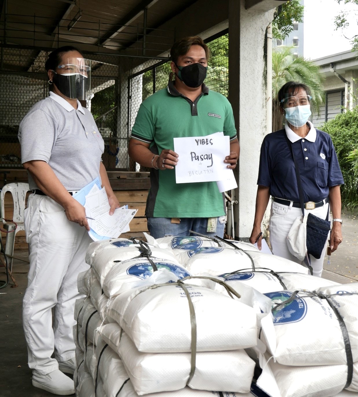 Tzu Chi volunteers flank a representative of VIBES Pasay as he claims rice. 【Photo by Matt Serrano】