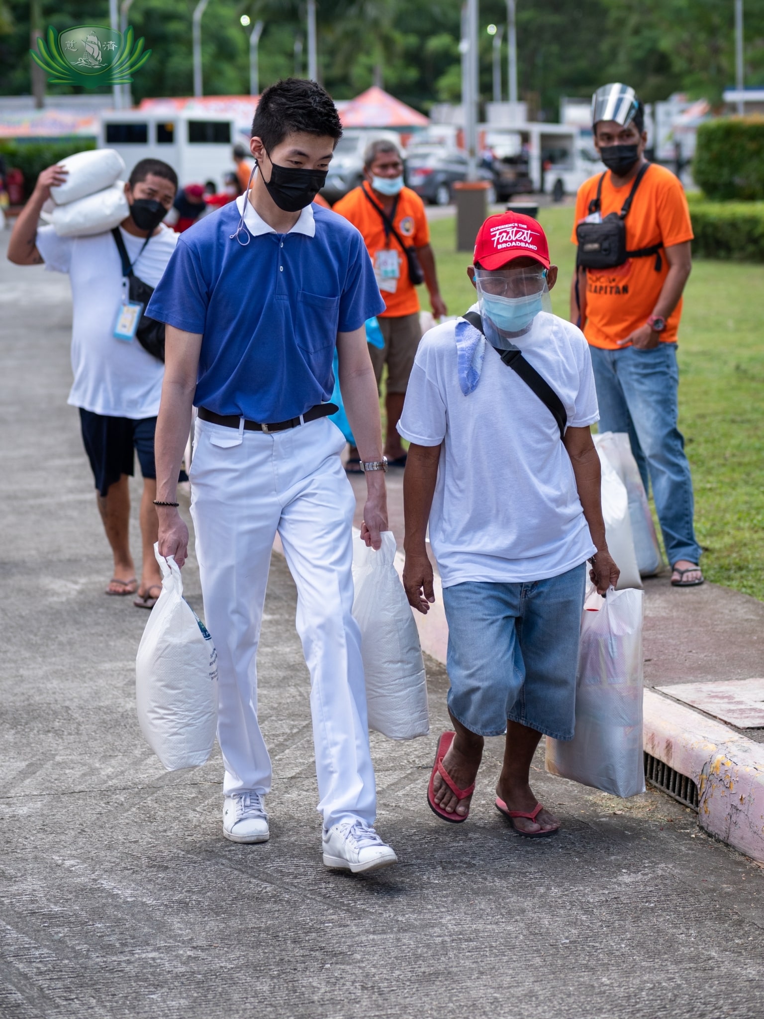 A volunteer assists a beneficiary with his sacks of rice. 【Photo by Daniel Lazar】