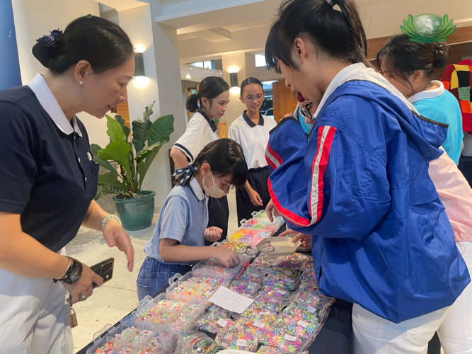Curious shoppers flock around the scholars’ area and choose beads for their personalized bracelets.  