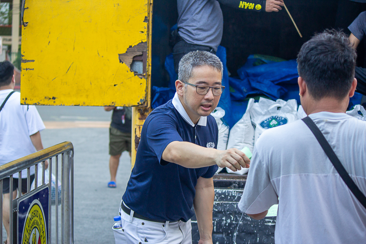 Tzu Chi volunteer Alvin Acero (in blue) assists beneficiaries claiming rice. 【Photo by Marella Saldonido】