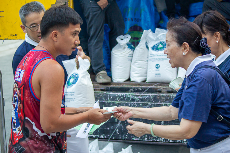 A Tzu Chi volunteer hands over a Puregold voucher worth P500 to a beneficiary. 【Photo by Marella Saldonido】