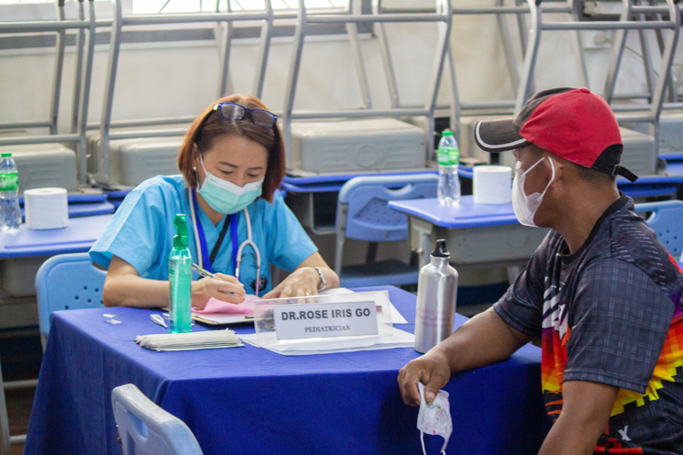 A regular of Tzu Chi medical missions, Dr. Rose Go attends to man who brought his young son for a checkup. 【Photo by Marella Saldonido】