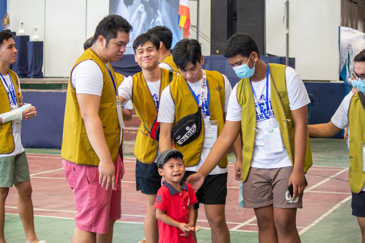 Ateneo de Davao University junior/senior high assistant basketball coach Martin Gian Maningo (second from left) and his players comfort a crying child at the medical mission. 【Photo by Marella Saldonido】