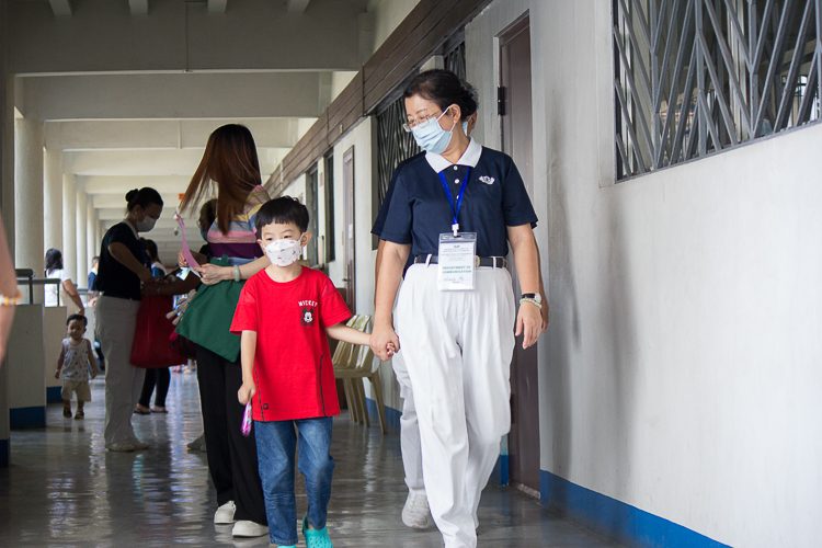 Tzu Chi volunteer Winnie Uy walks hand in hand with beneficiary-turned-donor Sam Anthony Tan.【Photo by Marella Saldonido】