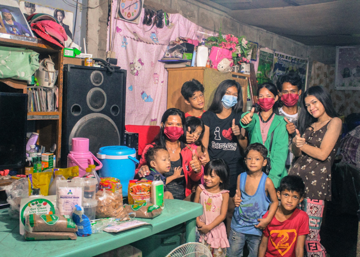 Here with family, Mylene Romano (seated with red sweater and black T-shirt) shares her rice and relief goods with fellow scavengers “so that they will also experience the blessings of the Tzu Chi Foundation.” 【Photo by Don Lopez】